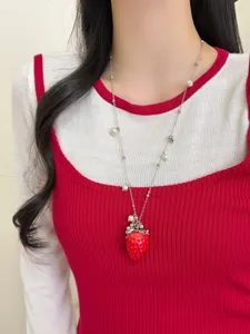 Gros plan détaillé du collier élégant avec pendentif fraise rouge et accents de perles.