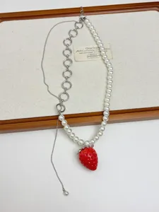 Vue détaillée du collier de perles fraise rouge chic, avec un design asymétrique tendance.