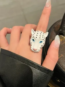 Squisito anello con testa di leopardo in smalto bianco, occhi blu e macchie nere, dettaglio.