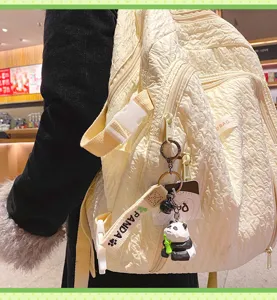 Detail view of cute wooden-style panda keychain hanging on stylish casual backpack.
