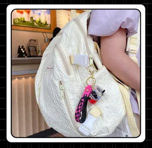 Detail shot of a chic quilted white backpack featuring a cute cartoon bubble tea keychain accessory.
