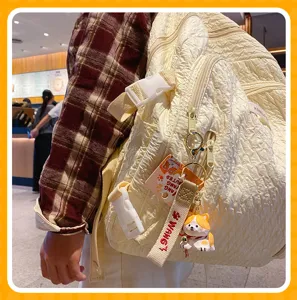 Detail view of a cute Corgi keychain pendant hanging on a stylish cream backpack strap.