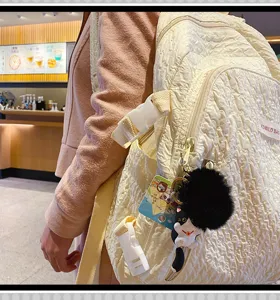 Detail view of the cute cat keychain and plush ball attached to the white casual backpack.