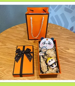 Cute panda keychain with orange gift box, stylish cartoon doll bag charm for women and couples.