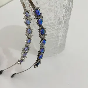 Dettaglio fascia per capelli in metallo pietra di luna stile punk con texture rugosa e pietre blu.