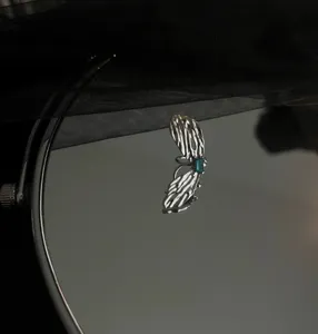 Close-up detail of a unique wing ear cuff with a blue gemstone on a mirror surface.