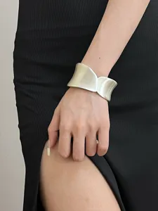 Wide matte silver metal cuff bracelet detail close-up showcasing modern brushed curved design.