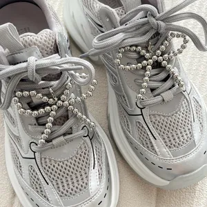 Grey silver fashion sneakers detailed with shiny metallic beaded bow shoe charms close up