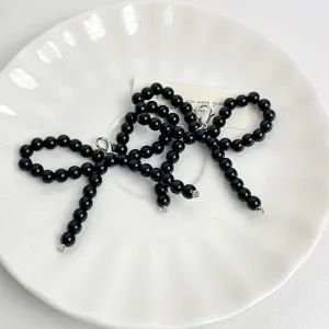 Black pearl beaded bow shoe charm accessory for stylish sneakers and footwear decoration.