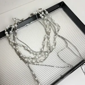 Close-up detail of the multi-layer pearl and metal bamboo-knot tassel necklace design.