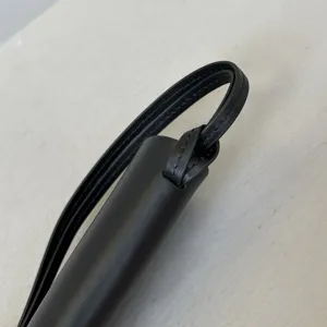 Close-up detail van zwarte lederen brilhoes nekriem met fijne stiksels en minimalistisch design.