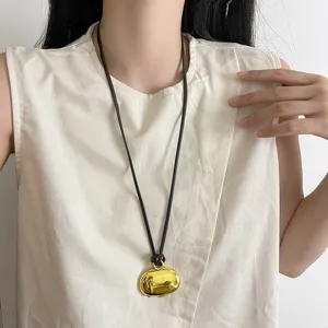 Close-up detail of the Korean long golden box pendant necklace with dark cord, elegant design.