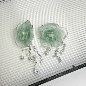 Detailansicht mintgrüner Mesh-Blumen-Ohrringe mit Perlen- und Kristallkettenquasten.