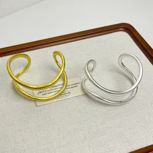 Nahaufnahme minimalistischer doppellagiger Metall-Armreifen in glänzenden Gold- und Silberfarben.