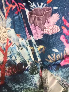 Detailed view of women printed leggings fabric with vibrant coral reef ocean pattern and seams.