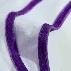Detailed view of purple trimmed white fabric garment material highlighting fine stitching texture.