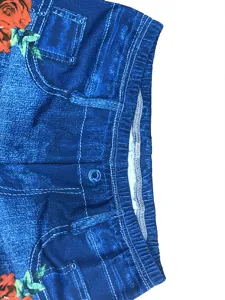 Close-up detail of high-waist faux denim shorts with stylish rose print and elastic waist.
