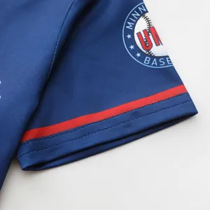 Kinder blaues Cheerleading Performance Trikot Detailfoto mit rotem Bündchenstreifen und Teamwappen.