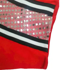 Detail shot of the cheerleading uniform featuring red fabric, striped trim, and sequin mesh.