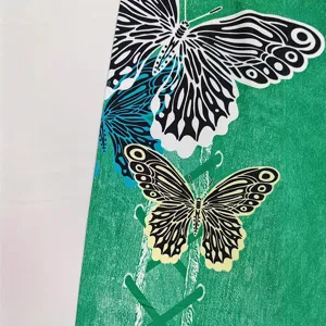 Close-up detail of women yoga leggings featuring vibrant green butterfly print fabric texture.