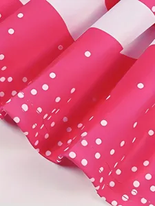 Close up of pink pleated skirt fabric with white polka dots for dance apparel and costume details.