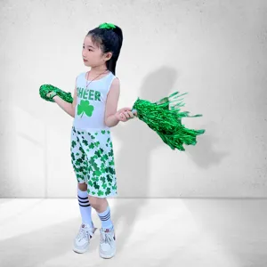 Detail view of children cheerleading uniform with green shamrock prints and cheer text.