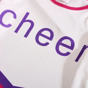 Kids cheerleading performance costume dress detail view in white with purple letters.