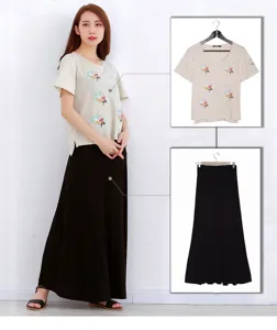 Detailed view of women's summer short-sleeve embroidered top and black maxi skirt outfit.