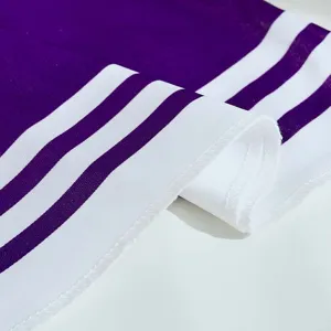Close-up of purple cheerleading uniform fabric featuring dual white stripes and clean stitching details.
