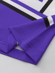 Vista detallada del dobladillo del uniforme morado, costuras limpias y tela de calidad.