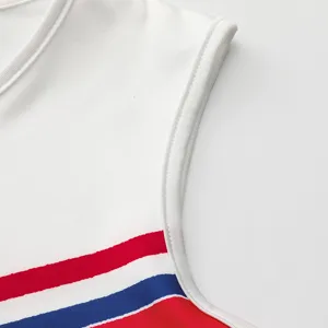 Détail costume cheerleading enfant haut blanc sans manches avec bandes rouges bleues sport.
