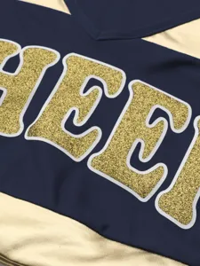 Close-up detail of cheerleading uniform with gold glitter letters and navy blue fabric.