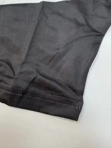 Close-up view of the black stretch fabric and neat double-stitched hem for apparel details.