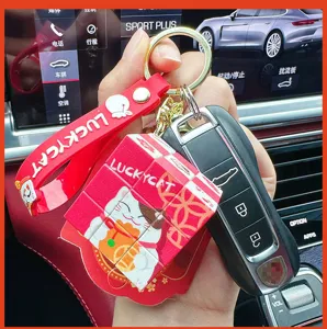 Detailed view of the cute lucky cat Rubik cube keychain pendant with red silicone strap.