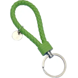 Portachiavi in pelle intrecciata verde con anello metallico, accessorio elegante per auto.