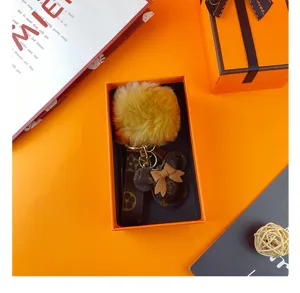 Luxus Plüschball Schlüsselanhänger mit Monogramm Anhänger im orangefarbenen Geschenk Karton.