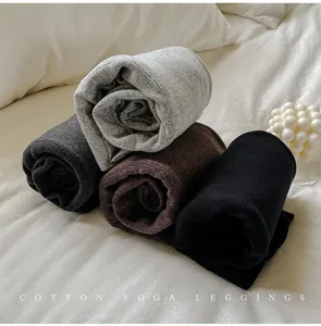 Détail de leggings de yoga en coton côtelé doux roulés proprement sur un lit blanc.