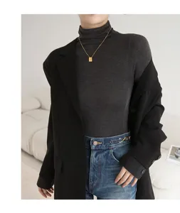 Close-up styling detail of women thermal turtleneck layered with black blazer and denim.