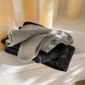 Gros plan d'un pile de collants d'hiver en laine épaisse gris et noir présentés sur étagère.