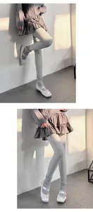 Detailed view of ribbed fleece lined tights worn with skirt in cozy warm indoor lighting scene.