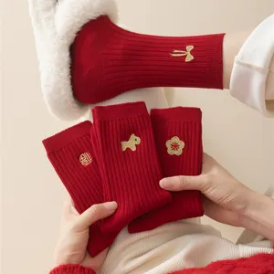 Close-up detail of red cotton socks with cute gold embroidered horse and flower patterns.