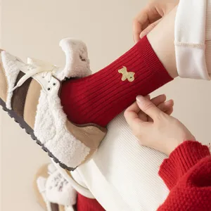 Close-up of red knit socks with gold horse embroidery, cozy winter footwear detail shot.