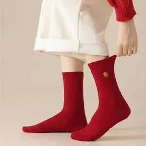 Detail view of winter red cotton ribbed socks with traditional golden embroidery for festive days.