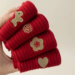 Close-up detail of red winter knit socks with gold embroidery, featuring festive New Year motifs.
