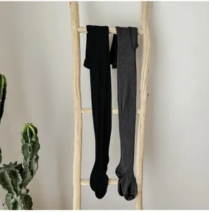 Detailaufnahme von schwarzen und grauen Thermo-Wollstrumpfhosen an einer Holzleiter.