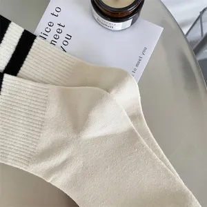 Close-up detail of women's off-white crew socks with classic black stripes, soft knit texture.