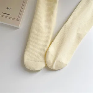 Detailed shot of women's solid light yellow ribbed mid-calf cotton socks with heel design.