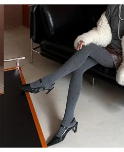 Collant grigi a pois abbinati a tacchi alti neri, vista dettagliata ed elegante delle gambe.