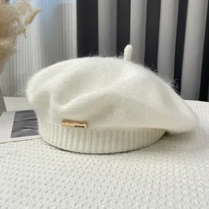 Detail shot of white fluffy knitted beret hat, cozy winter warm painter hat with metal tag.