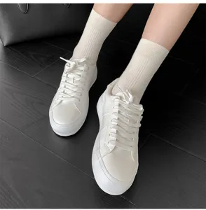 Vue détaillée de chaussettes unies côtelées en coton pour femme avec des baskets blanches.